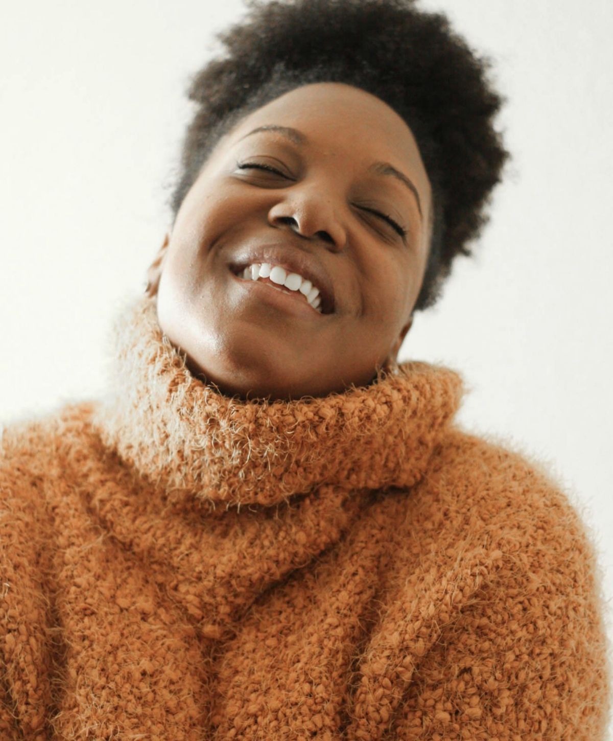 Smiling person in cozy sweater, joyful expression.