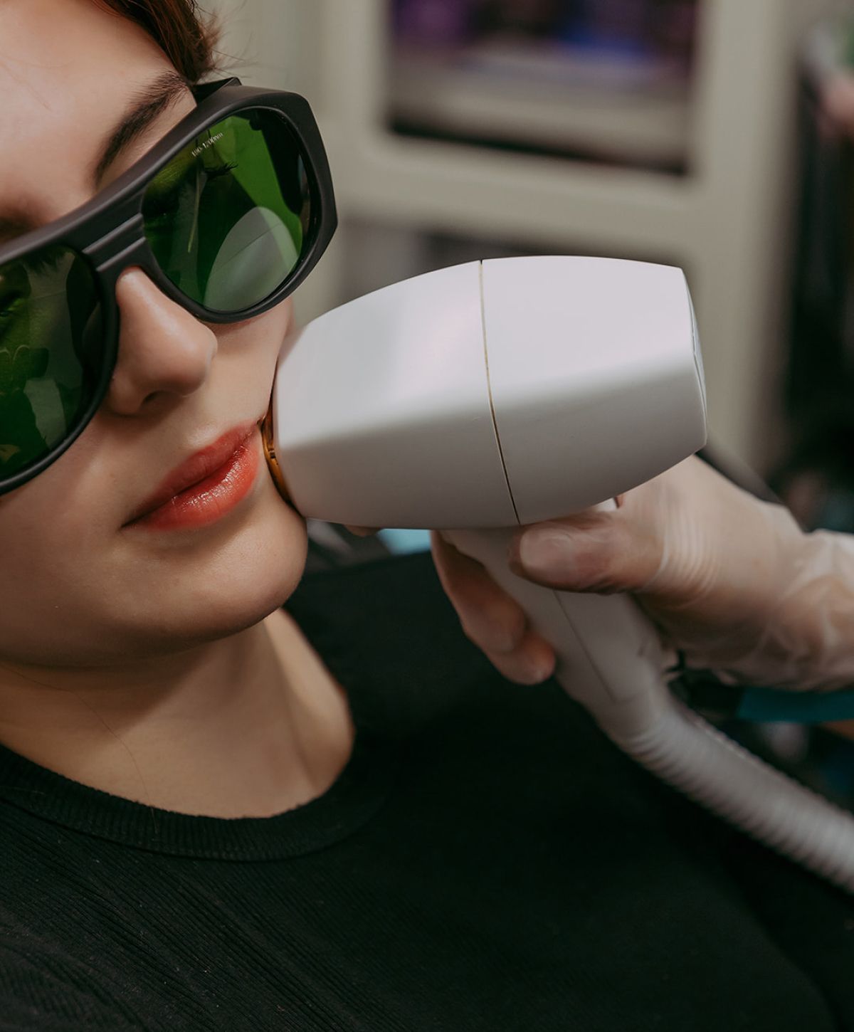 Person receiving facial treatment with laser device.