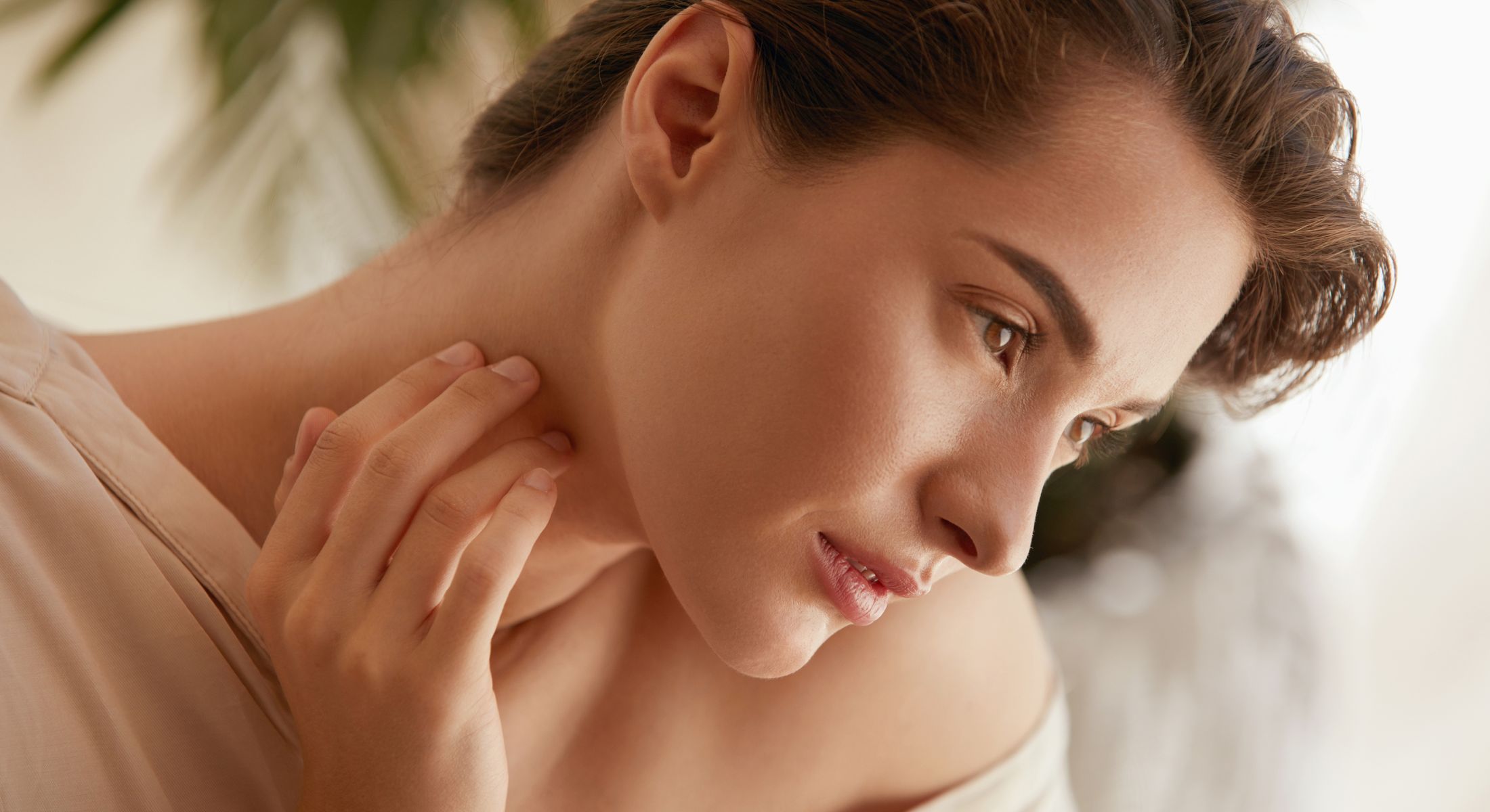 Profile of a woman touching her neck.