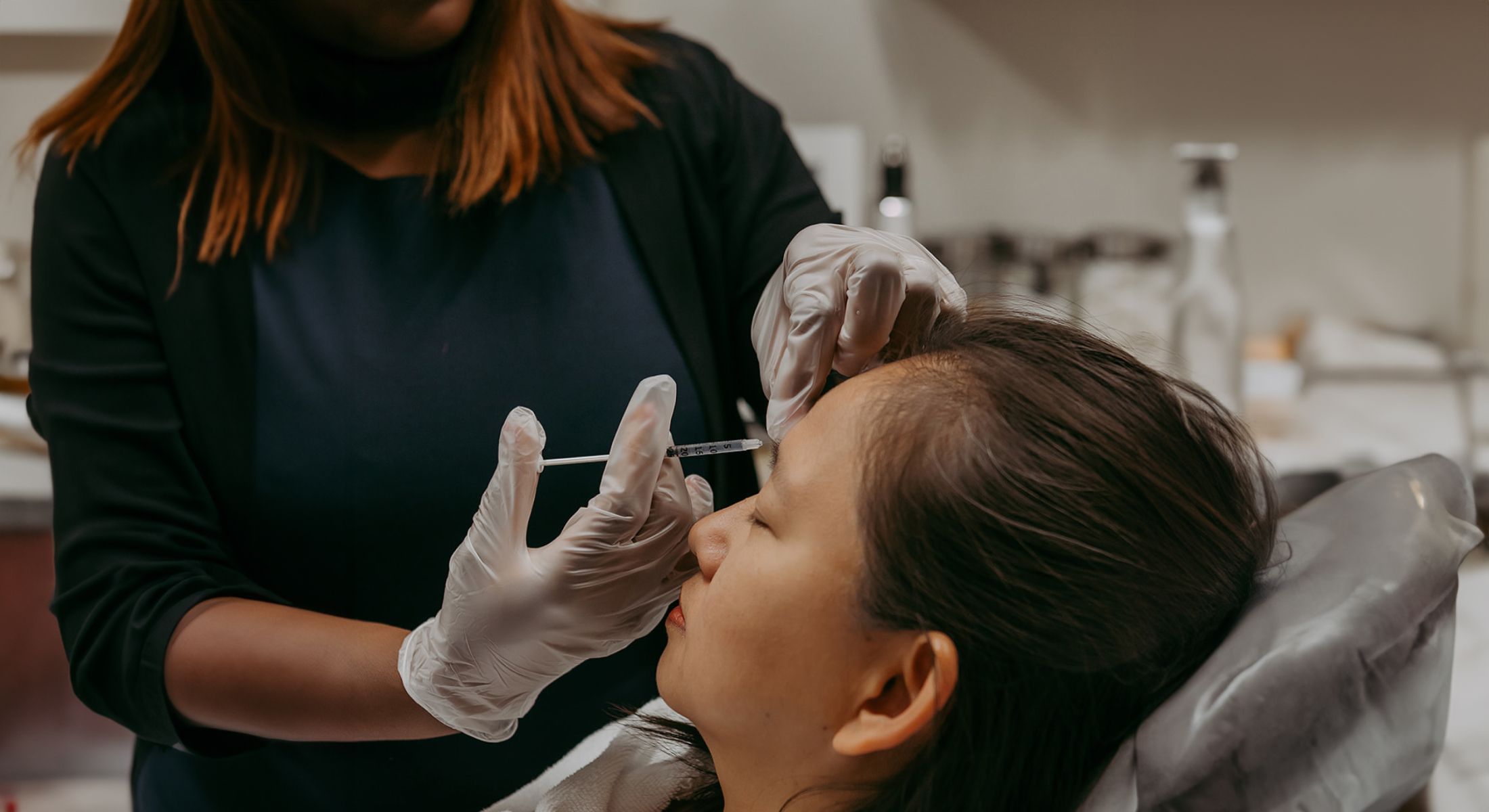 Administering cosmetic treatment to a client's forehead.